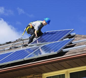 An expert from Solar Lights & More is installing solar panels on a house roof in Ocala, FL